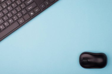 Tepede düz düz yatıyordu. Kablosuz siyah bilgisayar fare ve klavyenin yakın görünüm fotoğrafı. Mavi arkaplan üzerinde izole edilmiş ve boş boşluk var.
