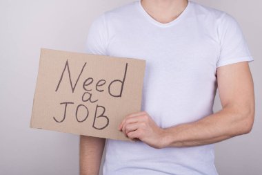 Açık kadro konseptine ihtiyacım var. Gri arka planda izole edilmiş mesajla günlük kıyafet giymiş bir adamın yakın plan fotoğrafı.