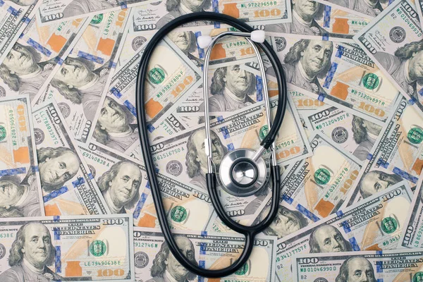 Expensive medicare or world global economical collapse concept. Top above overhead view photo of doc stethoscope lying on stack of us money