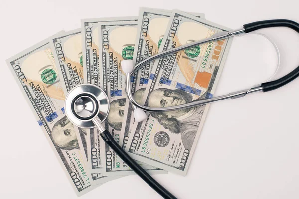 Global recession or medicare insurance concept. Top above overhead close up view photo of fan of american money ans medical equipment lying on doc table isolated over white background