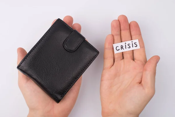No money no job concept. Pov Cropped close up overhead top view photo of male hands showing closed wallet and word crisis lying on palm isolated over grey background