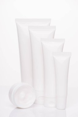 Kutu kutusu terapisi vücut spf reklam konsepti. Beyaz saf arkaplan üzerine izole edilmiş boş etiket kolajeni olan el yüz tüpleri koleksiyonunun dikey fotoğrafı