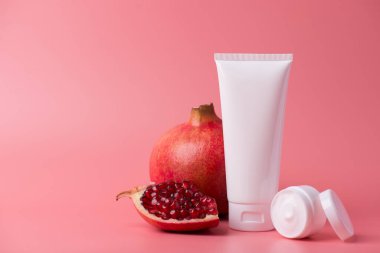 Vücut şımartma terapisi en az yaratıcı kavramdır. Sulu kırmızı nar arkaplanlı, boş boşluklu, plastikten yapılmış tonik ambalajlı fotoğraf.