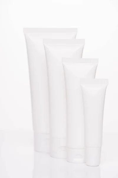 Collection of spray foam soap collagen creme concept. Vertical full length photo of four objects tubes for cosmetics with empty blank place for label text isolated over white pure background