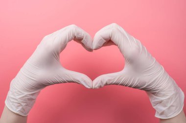 Hayat kavramını kurtar. Yukarıdaki en iyi pov. Pembe arka planda elleri eldivenlerle kalp yapan kadının yakın görüntüsü.