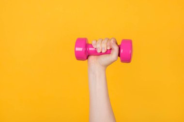 Konsept üzerinde çalışıyorum. Sarı arka planda pembe dambılı elinde tutan kararlı bir kadının kesilmiş fotoğrafı.