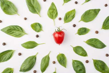 Tepede fesleğen yapraklarının, biberlerin ve beyaz arka planda izole edilmiş bir kiraz domatesinin fotoğrafı var.