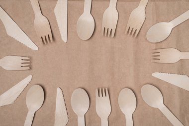 Üst tepede tahta çatal bıçak takımının yan yatmış fotoğrafı var. Merkezi el işi kağıdının arka planında izole edilmiş hale getiriyor.