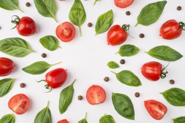 Yukarıdan bakıldığında fesleğen yapraklı, kiraz domatesli ve karabiberli beyaz arka planda izole edilmiş.