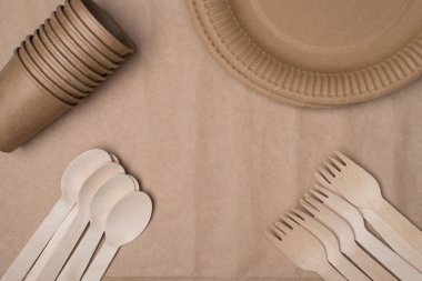 Yukarıdaki tepede tahta çatal bıçak, kağıt bardaklar ve tabaklar var. Köşelere yerleştirilmiş. Ortayı kağıt arka plan masasına izole edilmiş hale getiriyor.