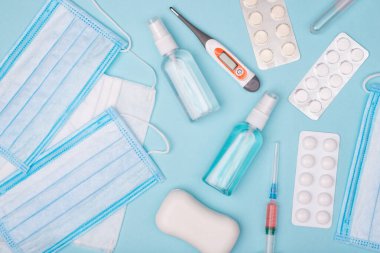 Coronavirus salgını konsepti. Yukarıda mavi arkaplanda gizlenmiş ilaç maskeleri ve sabun resimleri var.