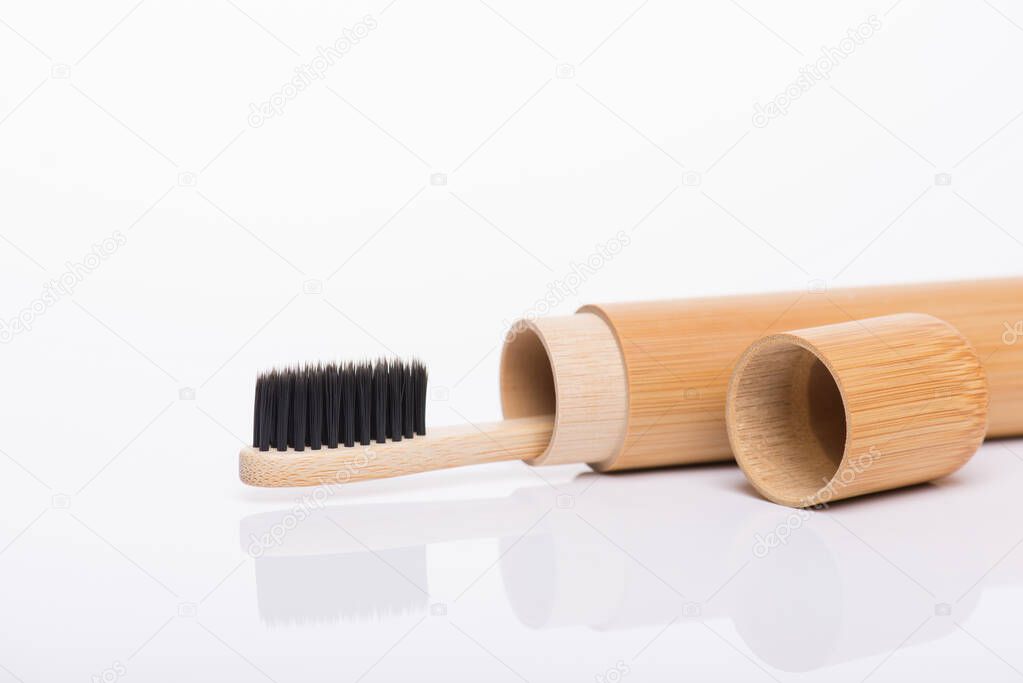 Close-up side profile macro view photo of eco-friendly bamboo packed in travel case black toothbrush isolated on white background