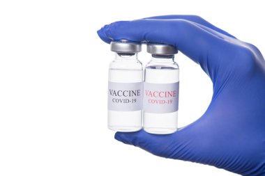 Coronavirus tedavisi konsepti. Doktorun elinde iki tüp COVID-19 aşısı tutarken çekilmiş yakın plan fotoğrafı beyaz arka planda izole edilmiş.