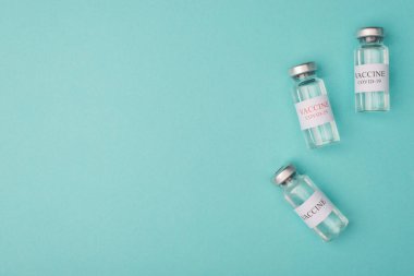 Sağlık ocağı gönüllülerin bağışta bulundukları aşıları test etmek için satın alıyor. Yukarıda mavi turkuaz arka plan kopyalama uzayında izole edilmiş COVID-19 aşı şişelerinin minimalist fotoğrafı var