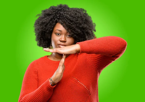 Beautiful african woman serious making a time out gesture with hands