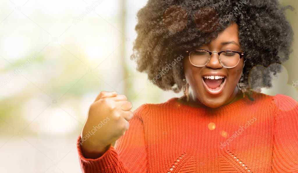 Beautiful african woman happy and excited celebrating victory expressing big success, power, energy and positive emotions. Celebrates new job joyful, outdoor