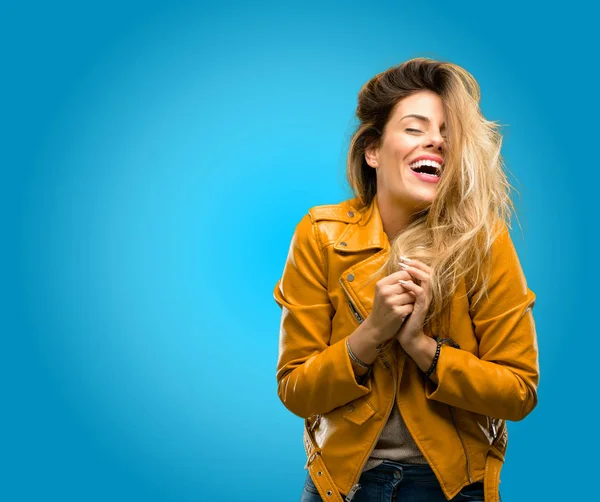 Beautiful young woman confident and happy with a big natural smile laughing, blue background