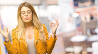 Güzel genç kadın meditasyon ve gevşeme restoranda ifade iki eliyle ok işareti jest yapıyor