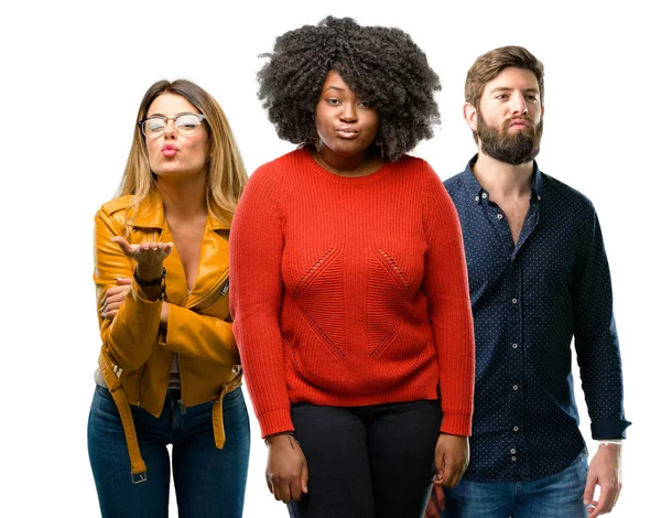 Group of three young men and women expressing love, blows kiss at camera, flirting