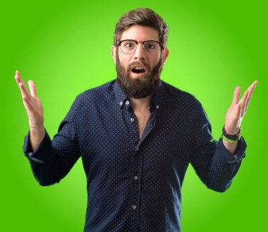 Büyük sakallı genç hipster adam panik ifade şokta, korkmuş ve korku yeşil arka plan üzerinde