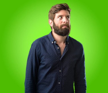 Büyük sakal şüphe ifade, adamla genç hipster şaşırtmak ve kavramı, yeşil arka plan üzerinde belirsiz gelecek merak ediyorum