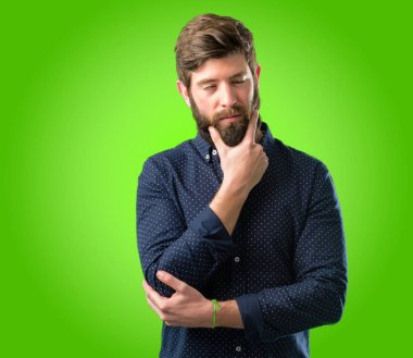 Büyük sakal şüphe ifade, adamla genç hipster şaşırtmak ve kavramı, yeşil arka plan üzerinde belirsiz gelecek merak ediyorum