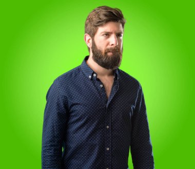 Büyük sakal şüphe ifade, adamla genç hipster şaşırtmak ve kavramı, yeşil arka plan üzerinde belirsiz gelecek merak ediyorum