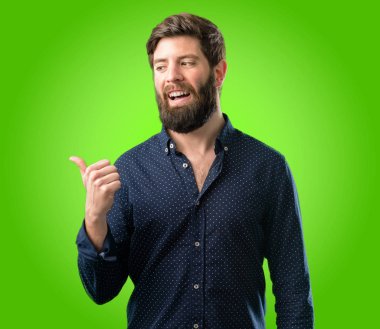 Yeşil arka plan üzerinde uzak yan parmağıyla işaret büyük sakallı genç hipster adam