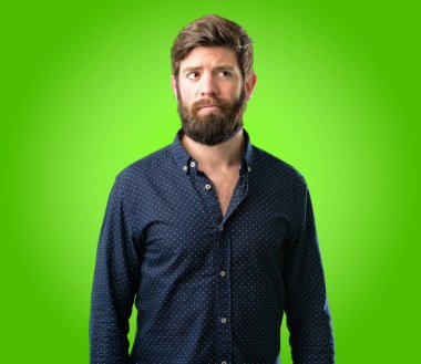 Büyük sakal şüphe ifade, adamla genç hipster şaşırtmak ve kavramı, yeşil arka plan üzerinde belirsiz gelecek merak ediyorum