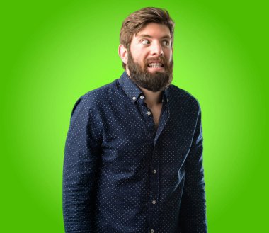 Kendinden emin ve mutlu yeşil arka plan üzerinde gülüyor büyük bir doğal gülümseme ile büyük sakallı genç hipster adam