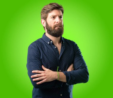 Sabırsız ifade, yeşil arka plan üzerinde dalgın ile kamera seyir büyük sakal gergin ve korkmuş ısırma dudaklı genç hipster adam