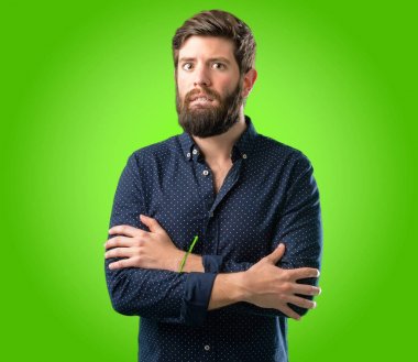 Sabırsız ifade, yeşil arka plan üzerinde dalgın ile kamera seyir büyük sakal gergin ve korkmuş ısırma dudaklı genç hipster adam