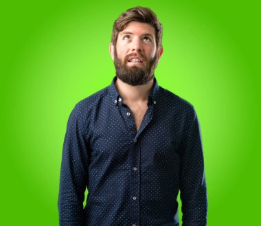 Kendinden emin ve mutlu bir büyük doğal büyük sakallı genç hipster adam gülümseme yeşil arka plan üzerinde komik ararken