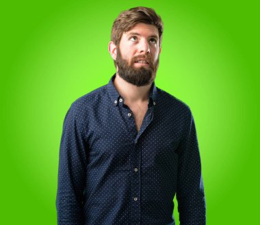 Kendinden emin ve mutlu bir büyük doğal büyük sakallı genç hipster adam gülümseme yeşil arka plan üzerinde komik ararken