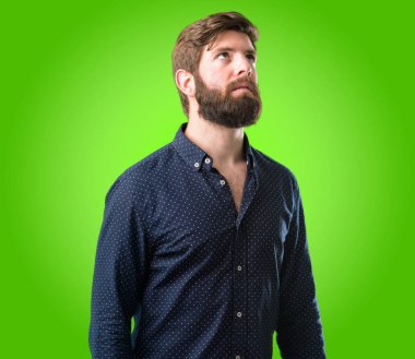 Kendinden emin ve mutlu bir büyük doğal büyük sakallı genç hipster adam gülümseme yeşil arka plan üzerinde komik ararken