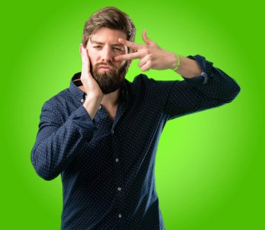 Parmaklarını göz kırpıyor ve bir öpücük yeşil arka plan üzerinde üfleme zafer jest olarak kameradan bakarak büyük sakallı genç hipster adam