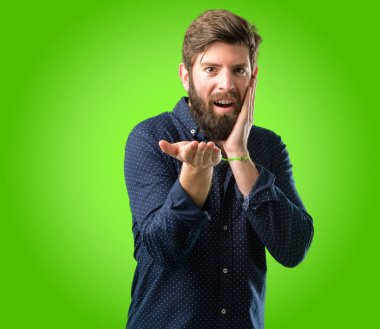 Bir şey yeşil arka plan üzerinde boş elinde tutan büyük sakallı genç hipster adam