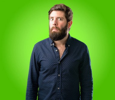 Şüpheci ve memnun olan büyük sakallı genç hipster adam bak ifade güvensizlik, şüphecilik ve şüphe yeşil arka plan üzerinde