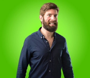 Kendinden emin ve mutlu yeşil arka plan üzerinde gülüyor büyük bir deli gülümseme ile büyük sakallı genç hipster adam