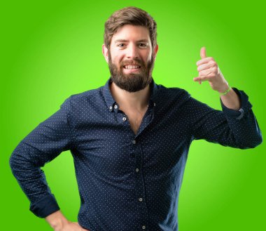 Mutlu ve heyecanlı bana jest telefon gibi yeşil arka plan üzerinde şeklinde el ile gösteren arama yapma büyük sakallı genç hipster adam