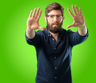 Kendinden emin ve mutlu eller fotoğraf makinesi için gösterilen, beste ve jest yeşil arka plan üzerinde çerçeveleme büyük sakallı genç hipster adam