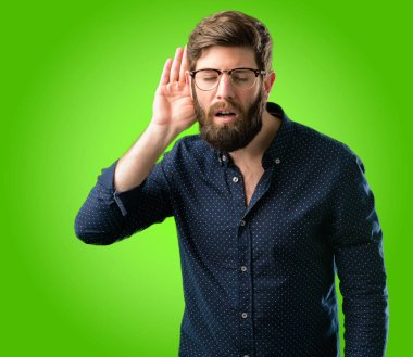 İletişim kavramı ve dedikodu yeşil arka plan üzerinde ifade ilginç haber dinlemek çalışıyor kulak yakınındaki elini tutarak büyük sakallı genç hipster adam