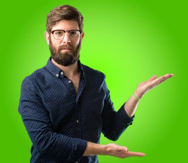 Kendinden emin ve mutlu bir büyük doğal büyük sakallı genç hipster adam gülümseme yeşil arka plan üzerinde girmek için davet