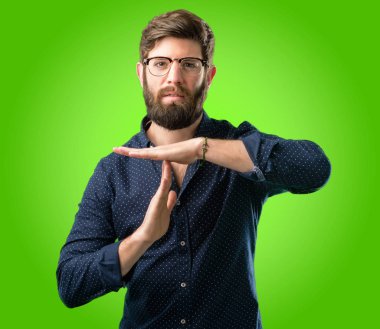 Yeşil arka plan üzerinde hareketi el ile bir zaman kazanmak ciddi büyük sakallı genç hipster adam