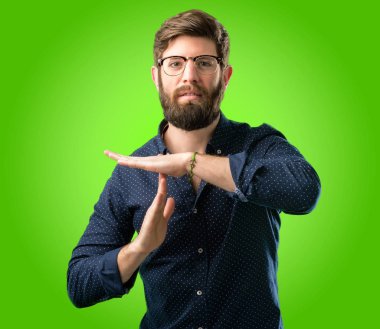 Yeşil arka plan üzerinde hareketi el ile bir zaman kazanmak ciddi büyük sakallı genç hipster adam