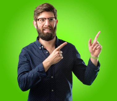 Yeşil arka plan üzerinde uzak yan parmağıyla işaret büyük sakallı genç hipster adam