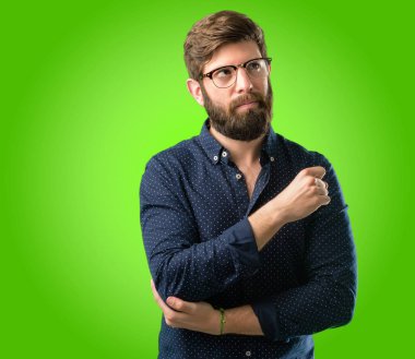 Yeşil arka plan üzerinde uzak yan parmağıyla işaret büyük sakallı genç hipster adam