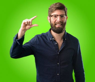 Büyük sakal çok küçük bir şey, holding ile genç hipster adam boyutu kavramı üzerinde yeşil arka plan