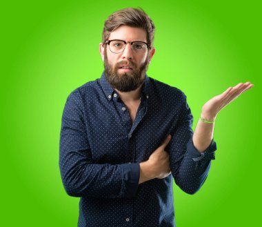 Büyük sakallı genç hipster adam rahatsız ve kızgın negatif duygu ifade, biriyle yeşil arka plan üzerinde rahatsız