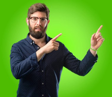 Yeşil arka plan üzerinde uzak yan parmak ile işaret büyük sakallı genç hipster adam